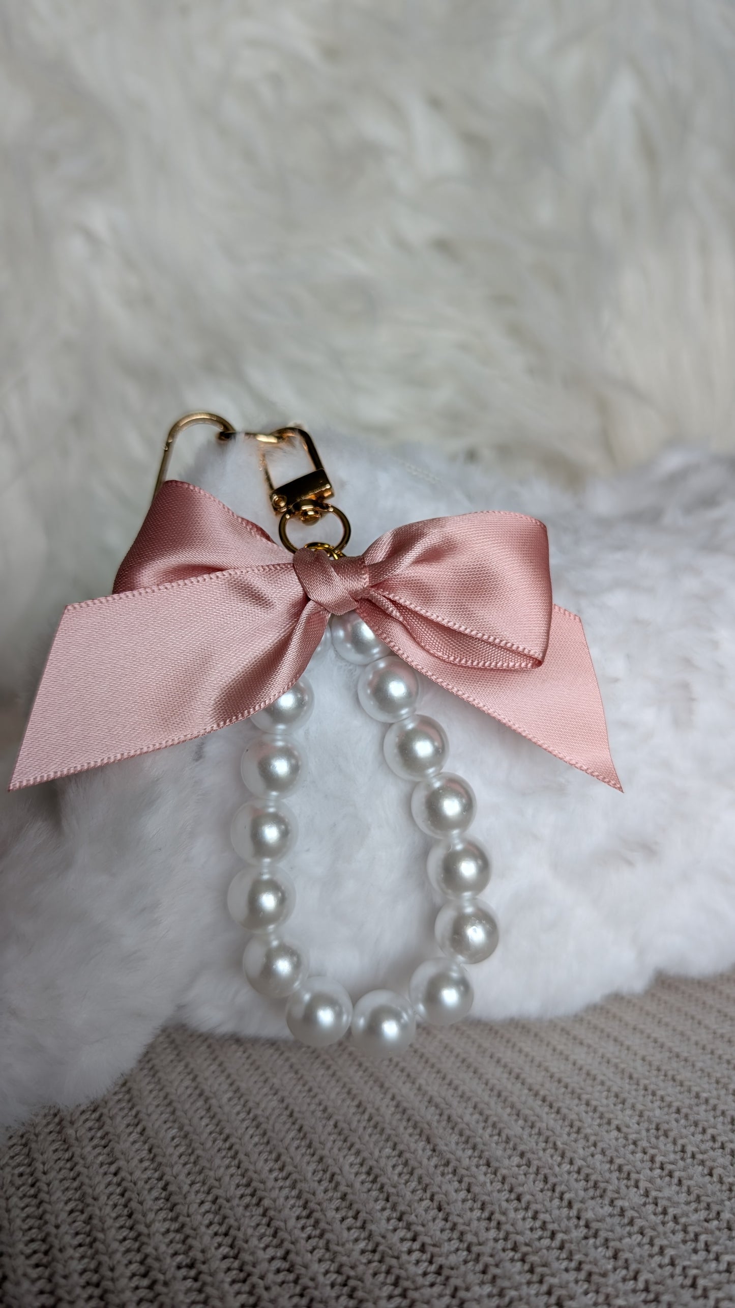 Pearl necklace with a pink bow on a textured surface