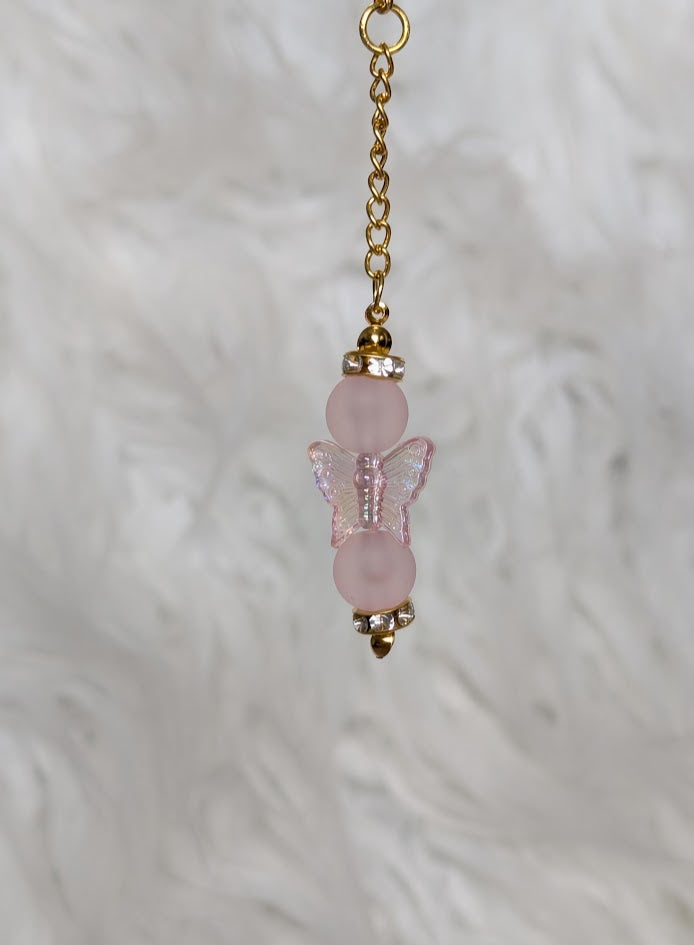 Pink butterfly charm with gold chain on a white background