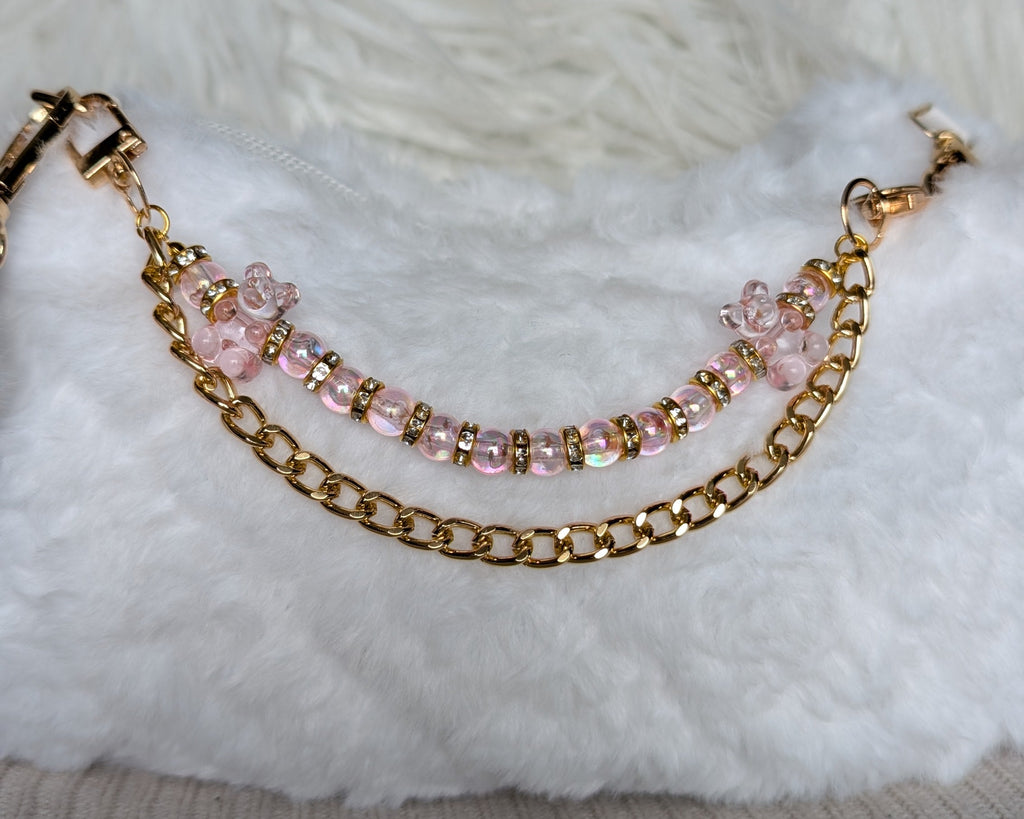 Gold chain bracelet with pink beads on a textured surface