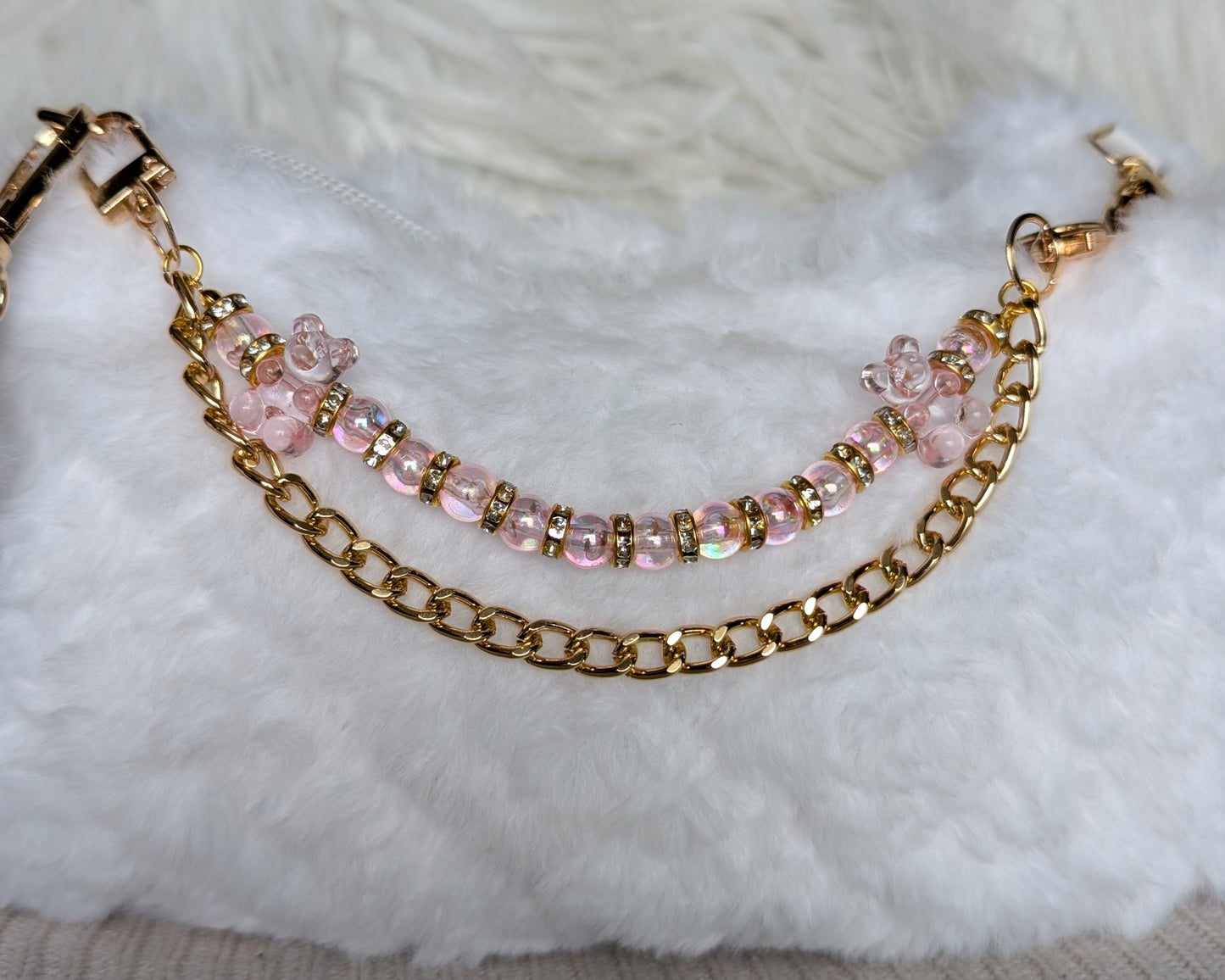 Gold chain bracelet with pink beads on a textured surface
