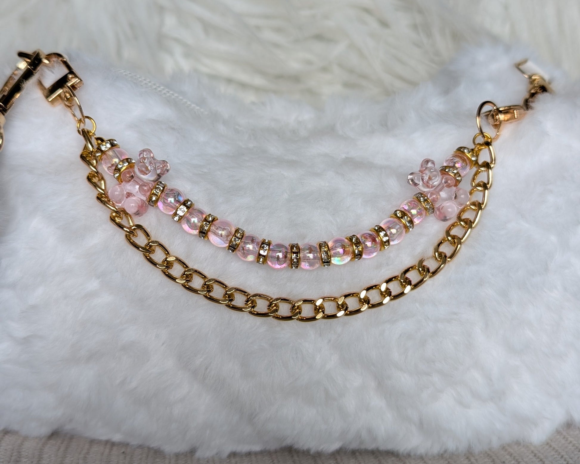 Gold chain bracelet with pink beads on a textured surface