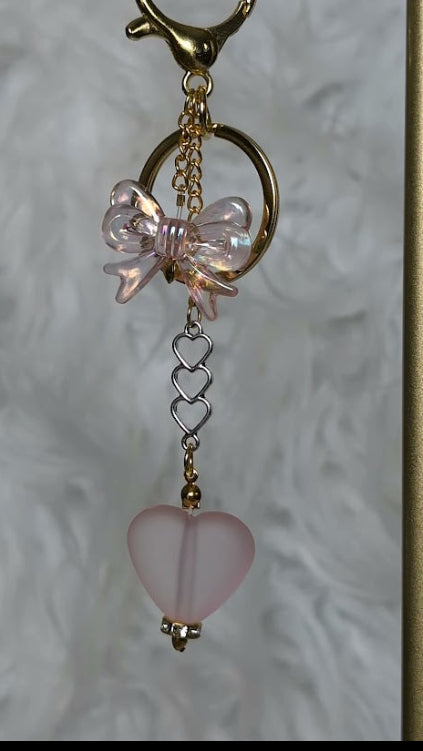 Keychain with pink butterfly and heart charm on a textured background