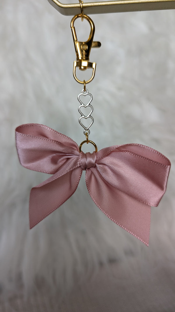 Pink bow keychain with gold clasp on a neutral background