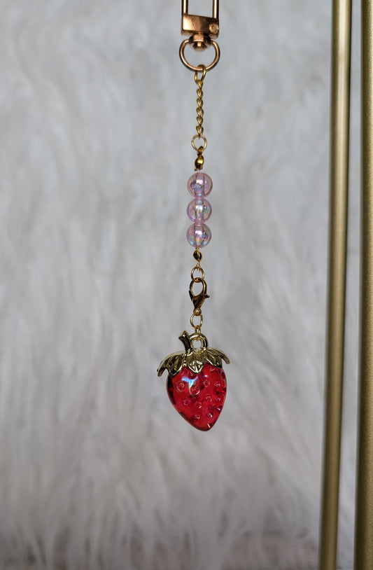 Strawberry-shaped keychain with beads on a neutral background