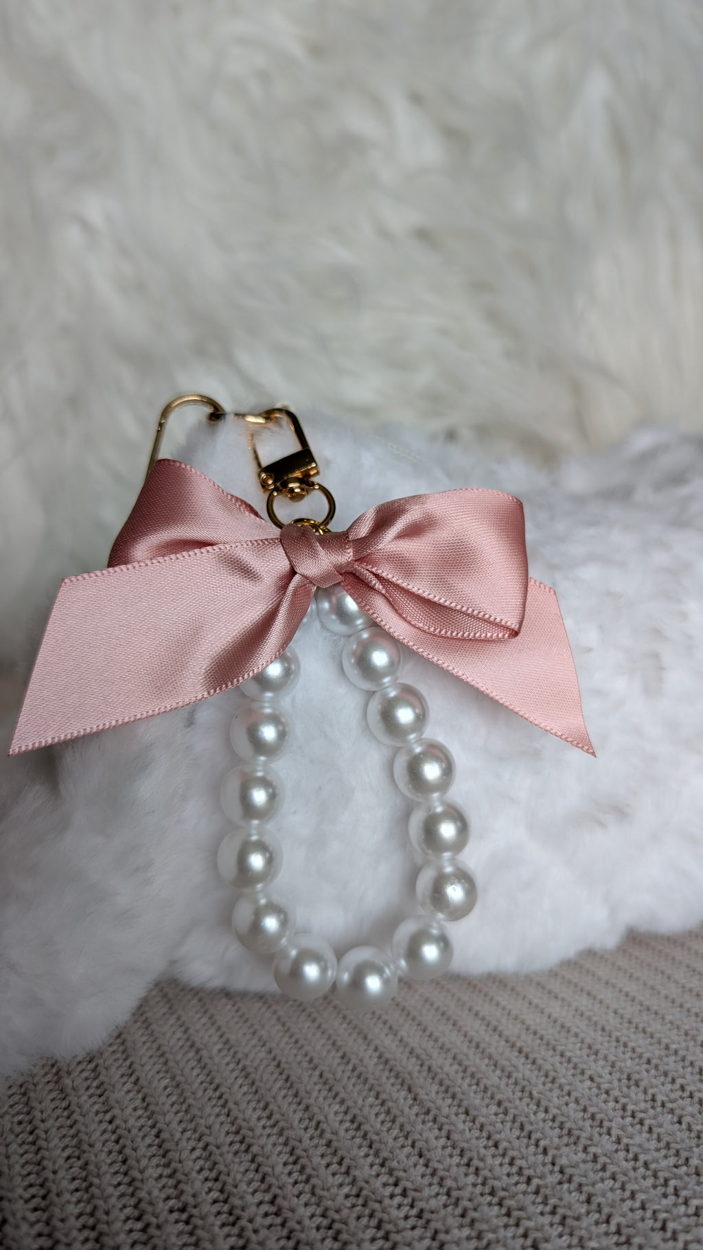 Pearl necklace with a pink bow on a textured surface