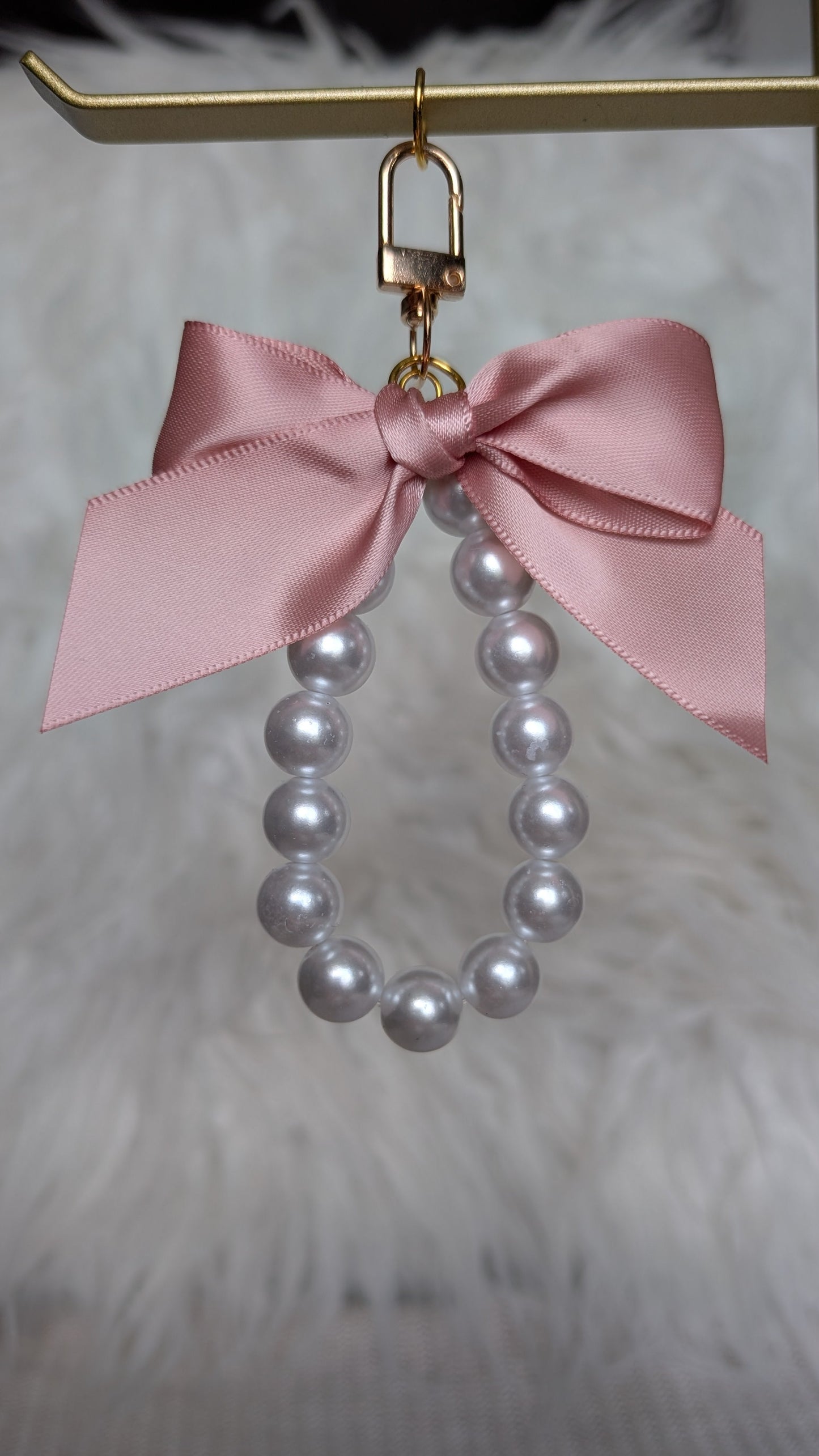 Pearl earring with a pink bow on a gold stand