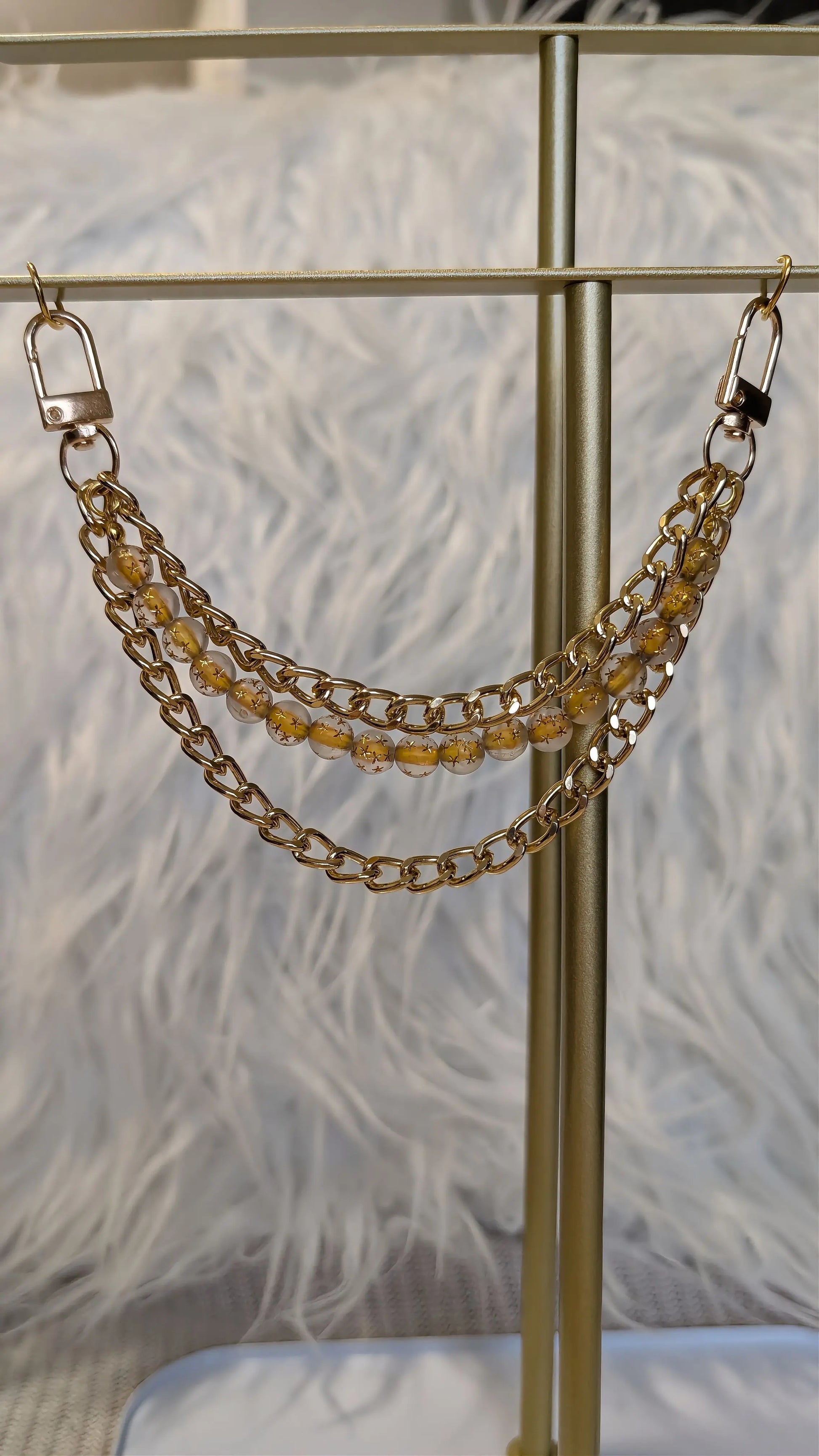 Gold chain accessory on a stand with a feathered background