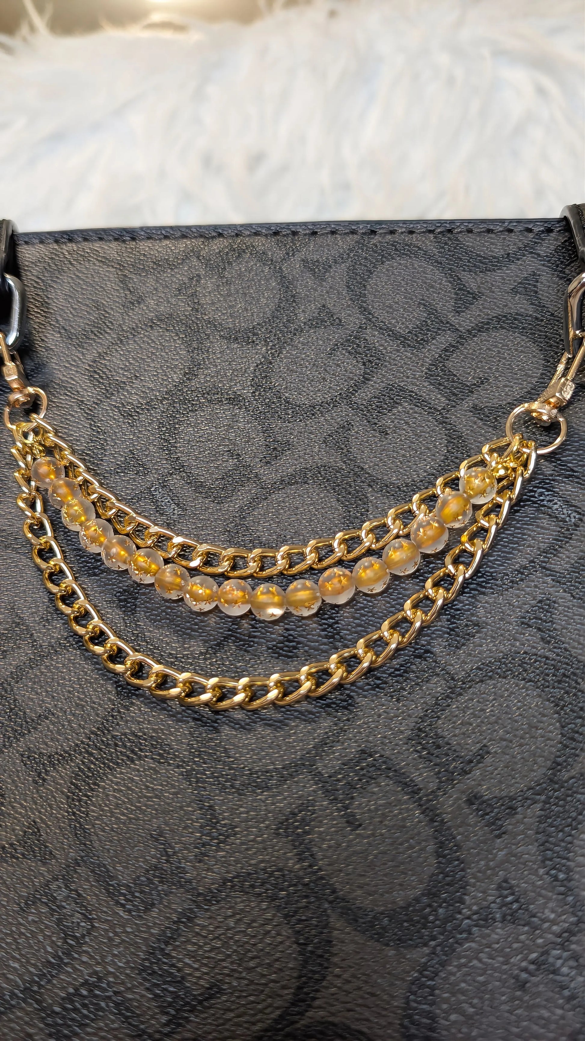 Gold chain with embedded stones on a black patterned surface