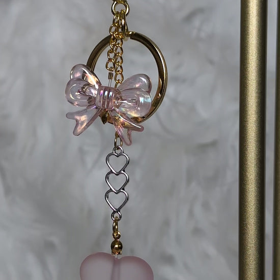 Keychain with pink butterfly and heart charm on a textured background
